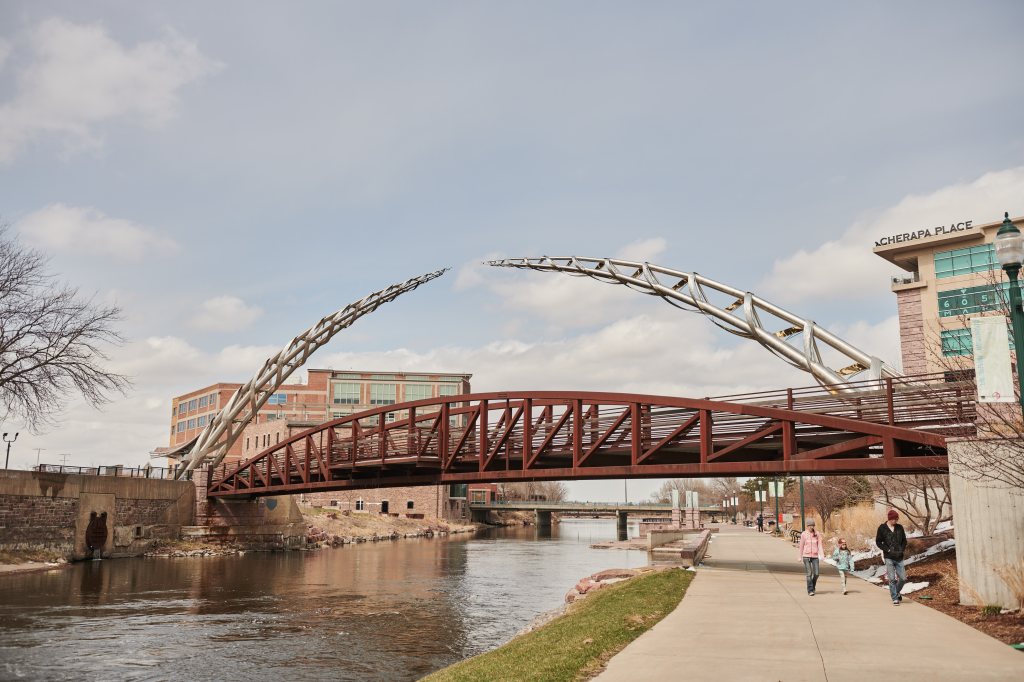 Pedestrians walk past the Arc of Dreams statue in Sioux Falls, South Dakota, U.S., Wednesday, April 15, 2020.